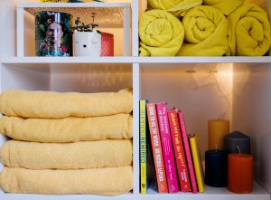 Shelves with house plants, yellow towels, candled and books