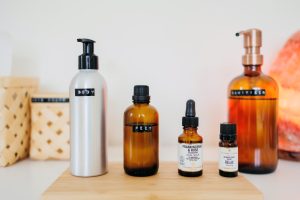 4 bottles of massage oils and hand sanitiser on wooden board