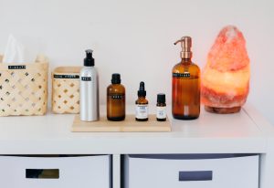 4 bottles of massage oils and hand sanitiser on wooden board