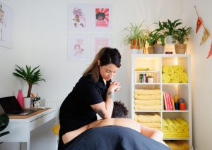 Female therapist massaging clients back with elbow in a massage room