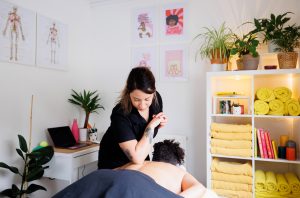 Female therapist massaging clients back with elbow in a massage room