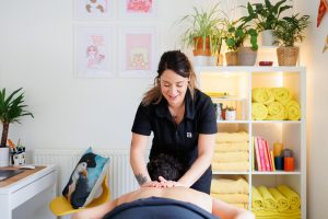 Female therapist massaging clients back with elbow in a massage room