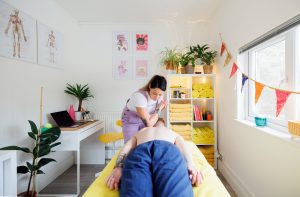 Massage therapist massaging client's back with her elbow in a massage room