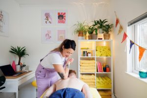 Massage therapist massaging client's back with her elbow in a massage room