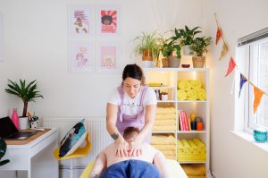 Massage therapist massaging client's back with her hands in a massage room