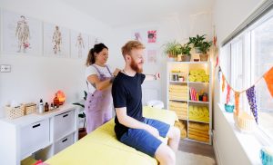 Massage therapist conducting a postural assessment of a male client's hips