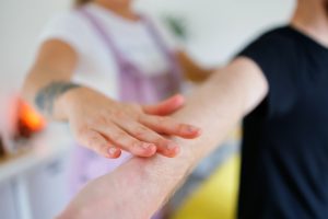 Massage therapist conducting a postural assessment of a male client's shoulder