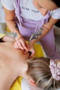 Therapist applying dry needles clients shoulder in a massage room
