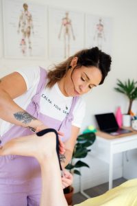 Therapist applying kinesiology tape to client's Achilles tendon
